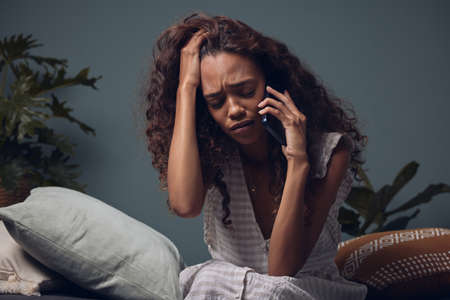 Im calling because I need help... a woman looking sad while talking on her cellphone.