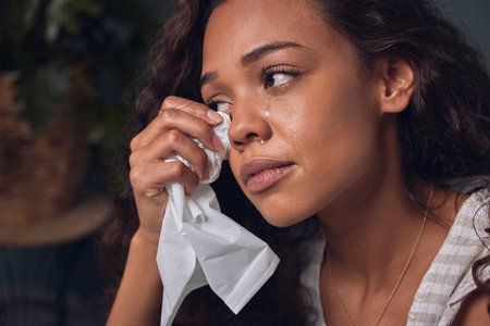 My heart is broken and I dont know how to put it back together. a young woman wiping her tears with...