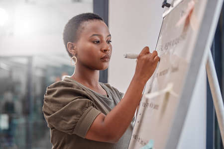 Ill write that down. a young businesswoman writing on a board at the office.