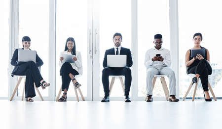 Getting together for all things business. a group of businesspeople using digital devices in an office.の写真素材