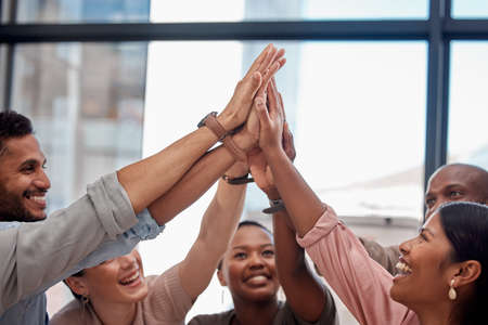 High five for a job well done. a group of young businesspeople giving each other a high five at the...