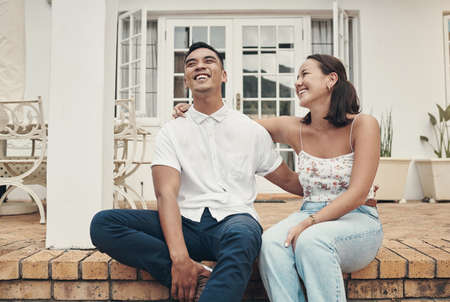 We never miss a bonding opportunity. a happy young couple sitting outside with their arms around each other during the day.の写真素材