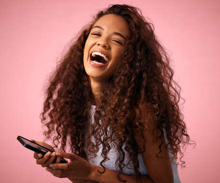 Id scroll through memes all day. Studio shot of a beautiful young woman using her cellphone while...