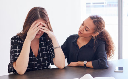 Youll get through this. a young businesswoman in distress being comforted by her coworker.の写真素材