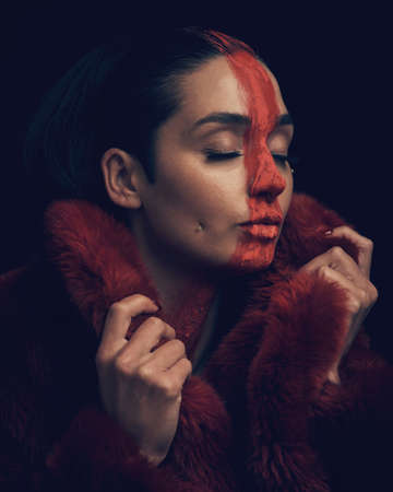 The privilege of a lifetime is being who you are. Studio shot of a young woman posing with paint on her face on a black background.の写真素材
