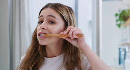 Keep that smile bright and white. a young woman brushing her teeth.の写真素材