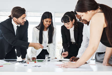 Deciding on who will be in charge of what. a group of businesspeople brainstorming together in an...