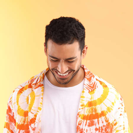Lets just be happy. a young man wearing a tie dye shirt while standing against a yellow background.の写真素材