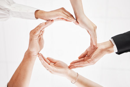 We need to stand together as a whole. Low angle shot of a group of businesspeople joining their hands together in a circular formation.の写真素材