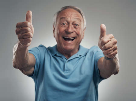 We should definitely do that again. a happy elderly man giving the thumbs up in a studio against a grey background.の写真素材