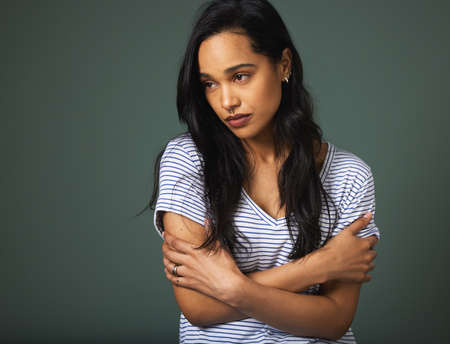 Its impossible to be positive all the time. an attractive young woman looking depressed against a green background in studio.の写真素材