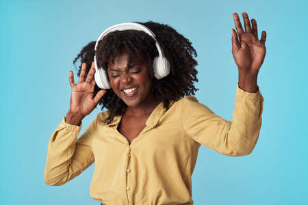 The best happiness boosting beats. Studio shot of a young woman using headphones and dancing against...