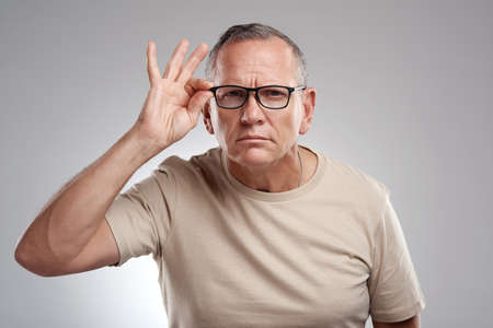 Hang on a minute... a handsome mature man standing alone against a grey background in the studio and...