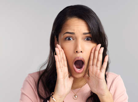 Everyone should know. a beautiful young woman shouting against a grey background.