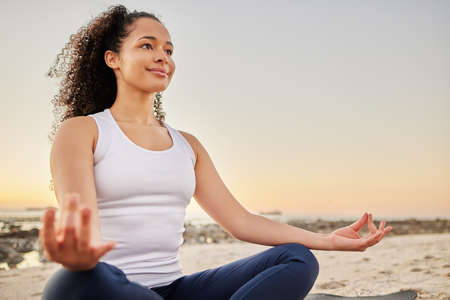 Shes on the path to inner peace. an attractive young woman meditating on the beach.の写真素材