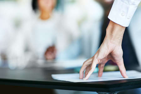 Business person touching report, paper or document while in a meeting, seminar or training at work. Hand of a confident manager, leader or boss doing a presentation in a workshop or conferenceの写真素材