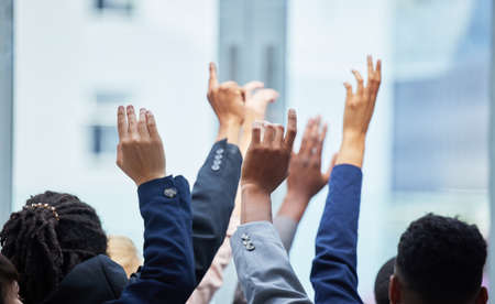Hands up if you believe. a diverse group of staff members with their arms raised.