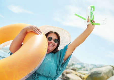 Race you to the water. a mature woman standing and holding a pool inflatable and snorkel during a...