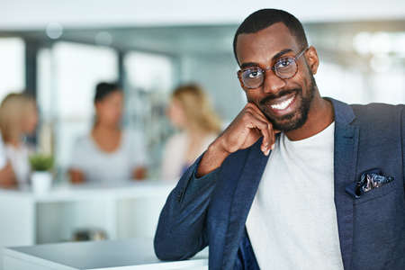 Confident, happy and smiling creative man standing in the office with a team of marketing agents in...