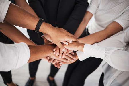 Teamwork leads to many victories. Closeup shot of a group of unrecognisable businesspeople joining their hands together in a huddle.の写真素材