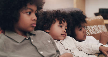 This movie has us hooked. three adorable little boys watching movies together at home.の写真素材