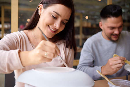 Forget the cinema, take the date to an art studio. a young couple painting ceramics in an art studio.の写真素材