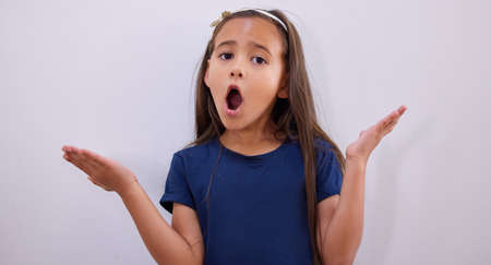 Why do I always get blamed for scattered toys. an adorable little girl shrugging while posing against a wall.の写真素材