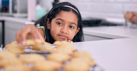 I just cant resist it. a little girl helping herself to freshly made cookies at home.の写真素材