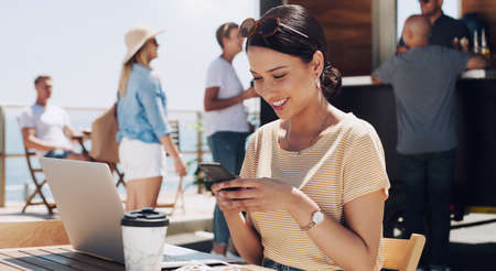 The sunshine and your texts are all I need. a young woman using her phone and working while sitting...