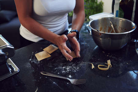 She loves getting her hands dirty. an unrecognizable young woman cooking homemade pasta at home.の写真素材