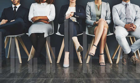 Interview group of corporate job applicants sitting in waiting room. Potential employees in recruitment agency stand by to see human resources manager. Professional businesspeople seeking employmentの写真素材