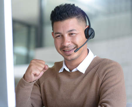 Proving his skills yet again as an expert salesman. a young call centre agent cheering while working in an office.の写真素材