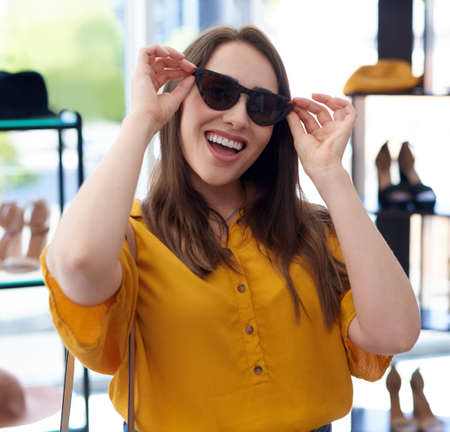 Im always ready for some retail therapy. Portrait of a young woman trying on sunglasses while shopping in a store.の写真素材