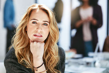 Serious, focused and confident businesswoman sitting in a modern business office workplace. Portrait...