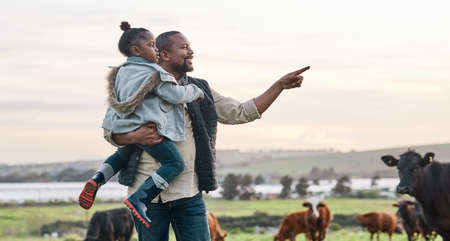 The simplest life makes the sweetest memories. a mature man carrying his adorable daughter on a cow farm.の写真素材