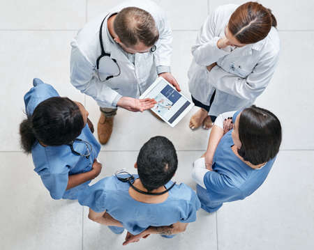 Discussing healthcare plans and programs. High angle shot of a group of medical practitioners using...