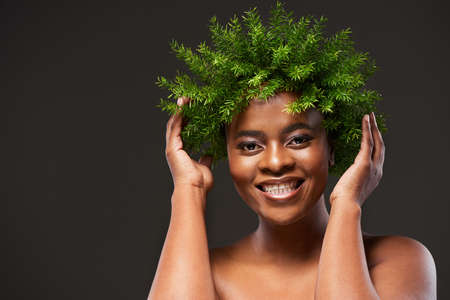 Make happiness as routine as your beauty regime. Studio shot of a beautiful young woman wearing a leaf wreath on her head against a grey background.の写真素材