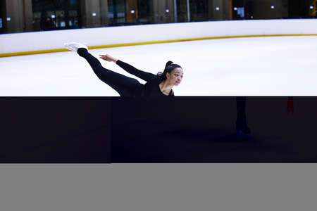 Some reach for the stars, others glide across them. a young woman figure skating at a sports arena.の写真素材