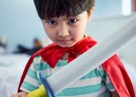 I will fight the baddies. Portrait of an adorable little boy pretending to be a superhero while playing at home.の写真素材