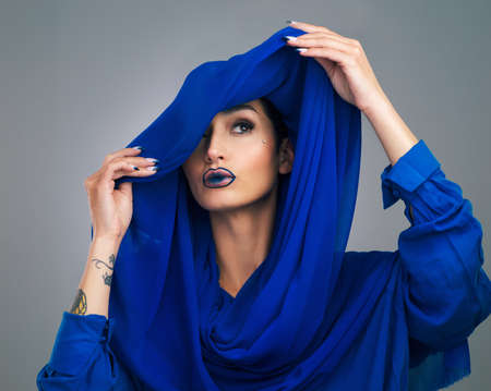 Think beautifully and the body will follow. Studio shot of a beautiful young woman looking thoughtful while posing against a grey background.の写真素材