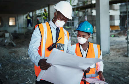 Promoting teamwork promotes productivity. a young man and woman going over building plans at a...