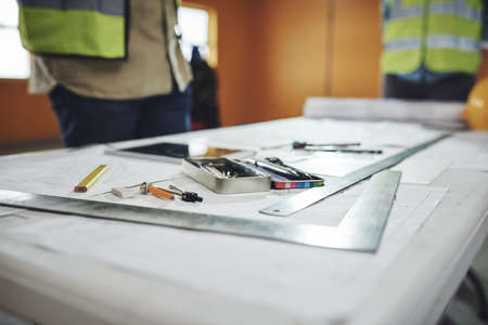 Here comes another winning construction project. various tools and a blueprint on a table at a...