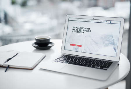 The time to get growing is now. a laptop displaying a business related website on a table at home.の写真素材