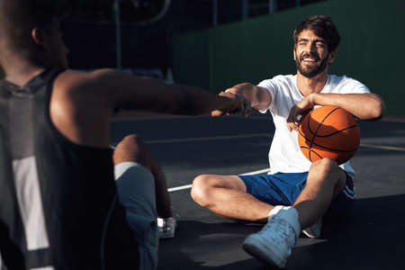 That was a good game. a sporty young man giving his teammate a fist bump on a basketball court.