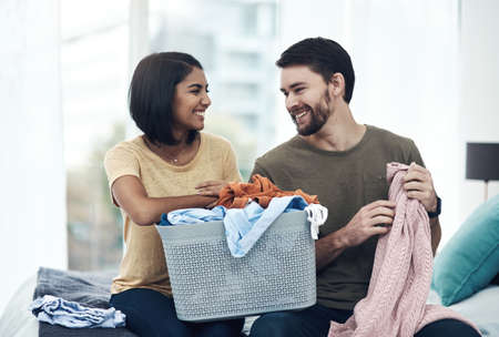All you need is love and clean laundry. a young couple doing laundry together at home.の写真素材