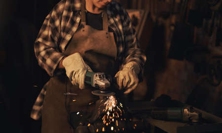 Women are stronger than steel. a woman using an angle grinder while working at a foundry.の写真素材