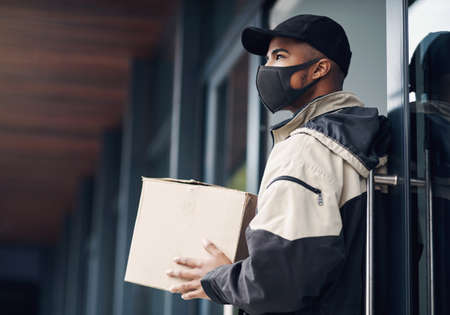 Is anybody home. a masked young man delivering a package to a place of residence.の写真素材