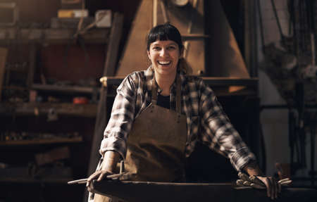 The best blacksmith in the business. Portrait of a confident young woman working at a foundry.の写真素材