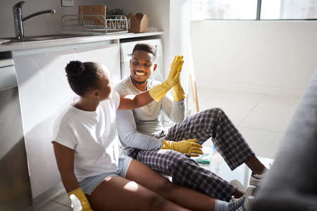 Divide the task, share the reward. a young couple giving each other a high five after doing chores together at home.の写真素材