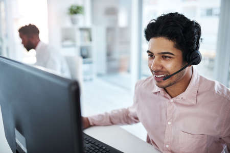 He knows what to say to make all the sales. a young call centre agent working on a computer in an...